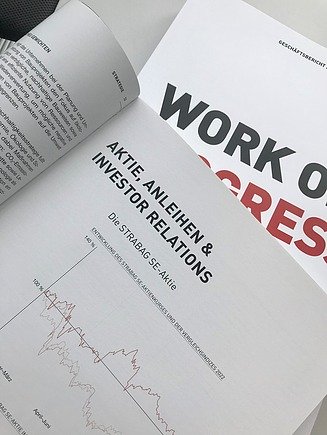 Foto van groene bergflanken met een lange verkeersweg. Op de bergflanken zie je dennenbomen.