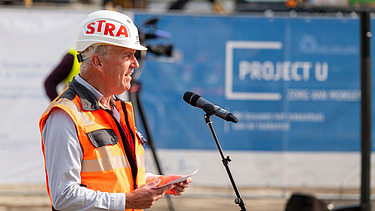 Foto van de speechende Financieel directeur STRABAG Belgium Regio Zuid/West Glenn De Letter tijdens tijdens de eerste spadesteek van de nieuwe projecten op UZ Gent.