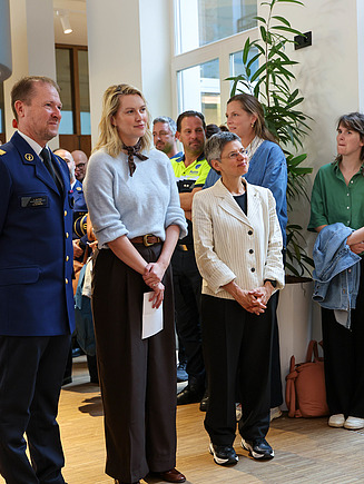 Foto van het luisterend publiek met vooraan Els van Doesburg (burgmeester van Antwerpen), Serge Muyters (korpschef) en Cathy Berx (gouverneur van Antwerpen) tijdens de plechtige opening van het Regiokantoor Politie Antwerpen Regio West.