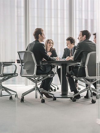 Foto van een managementteam dat in een vergaderruimte rond een grote tafel zit te vergaderen. 