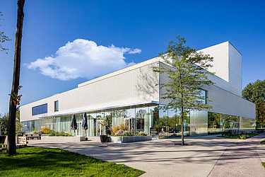 Een foto van de voorgevel van het nieuwe Leietheater in Deinze, met groene omgevingsaanleg.