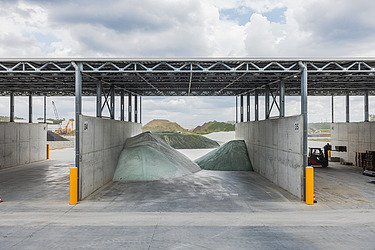 Een loods op de nieuwe site van de glasrecyclagefabriek voor GRl Glass Recycling and Logistics in Beringen, aan het Albertkanaal. In de loods zie je verwerkte glasbergen. 